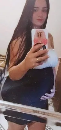 This live wallpaper features an image of a pregnant lady taking a selfie in front of a mirror with a mesmerizing abstract patterned picture in the background