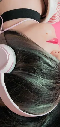 This phone live wallpaper features a close-up photo of a woman lying on a bed, wearing headphones and surrounded by a predominantly pink, white, and green color scheme