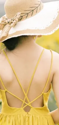This phone live wallpaper shows a peaceful field of yellow flowers with a woman wearing a wide sunhat and an open-back dress