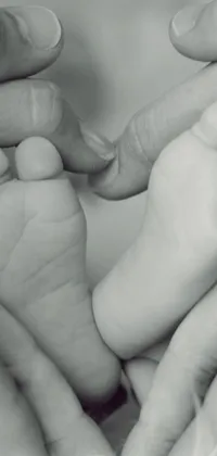 This phone live wallpaper features a heartwarming close-up of a baby's foot being held tenderly by an adult
