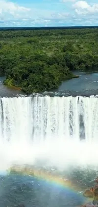 This live wallpaper depicts a picturesque aerial view of a waterfall with a splendid rainbow in the middle
