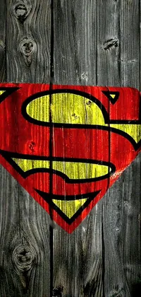 This phone live wallpaper features a classic Superman logo painted onto a wooden fence