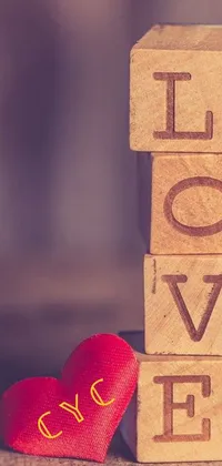 This phone live wallpaper features a vibrant red heart next to a wooden block bearing the word "love"