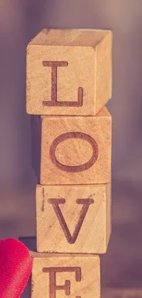 This phone live wallpaper showcases a wooden block with the word "love" on it, set against a close-up image of stacked wooden objects