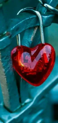 This phone live wallpaper showcases a vibrant image of a heart-shaped padlock attached to a metal fence, featuring hues of teal, silver, and red