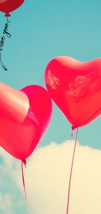 This lively phone live wallpaper features two heart-shaped red balloons floating against a blue sky