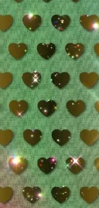 This phone live wallpaper features a lovely bunch of hearts placed on a golden reflective plate, amidst dreamy green sparkles