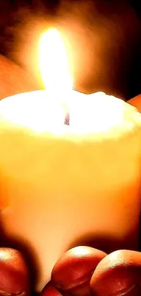 Enhance your phone's appearance with this stunning live wallpaper where a person holds a lit candle in their hands