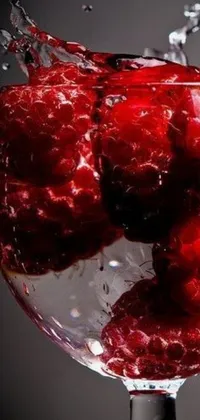 This gorgeous live wallpaper showcases a clamorous close-up of a glass filled with refreshing water and tantalizing raspberries