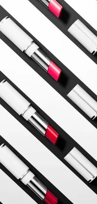 This phone live wallpaper features a group of lipsticks displayed on a black and white striped surface