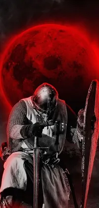 Looking for an epic medieval phone wallpaper? Look no further than this stunning digital artwork featuring a sword-wielding warrior sitting on the ground clutching his shield amidst a dramatic blood red crescent moon