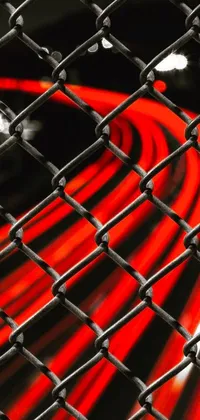 This phone live wallpaper features a hypnotic close up of a chain link fence in black, white, and red colors, with blurred lights in the background adding movement and energy