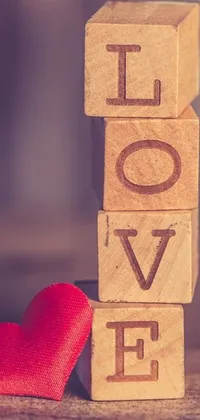 This phone live wallpaper showcases a wooden block with the word love and a red heart, alongside an elegant picture from Pexels