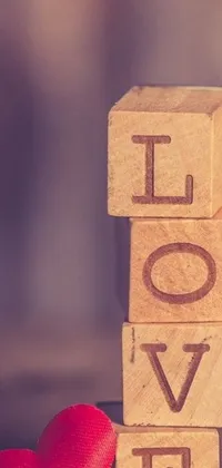 This stunning phone live wallpaper boasts a wooden block with the word "love" etched on it sitting beside a red heart, adding a romantic twist to your screen