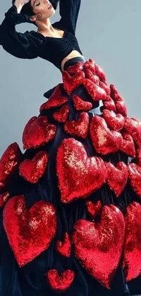 This live wallpaper boasts a stunning woman adorned in a red and black heart-patterned dress, captured from a high-fashion photo shoot