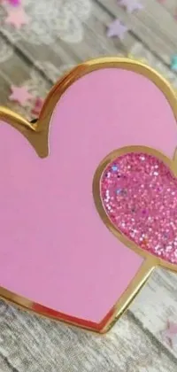 This stunning phone live wallpaper features a pink heart-shaped pin delicately sitting on top of a rustic wooden table