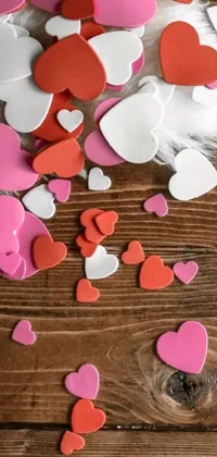Get ready to fall in love with this adorable phone wallpaper featuring a wooden table layered with dozens of bright pink and red hearts