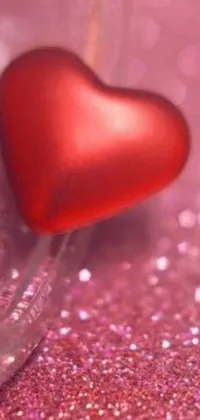 This gorgeous phone live wallpaper features a close up of a red heart floating in a sparkling glass, surrounded by a pink glittering background