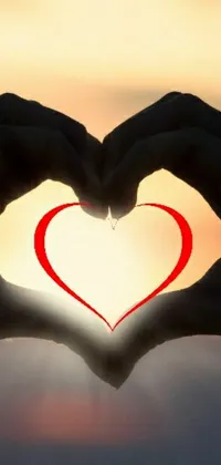This stunning live wallpaper for your phone showcases a heart shape made by someone's hands, indicating an intense emotional connection
