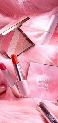 This live phone wallpaper showcases an array of cosmetics arranged on a fluffy pink fur