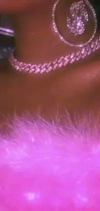 This phone live wallpaper features a close-up shot of a woman wearing a vibrant pink dress while adorned in rapper bling jewelry and luxurious fur