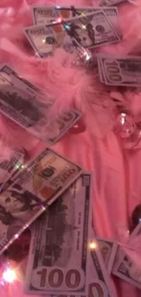 This phone live wallpaper features a pile of cash sitting on top of a pink blanket