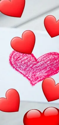 This charming live wallpaper features a heart drawn with crayons on a piece of paper, surrounded by pink and red hearts in the background
