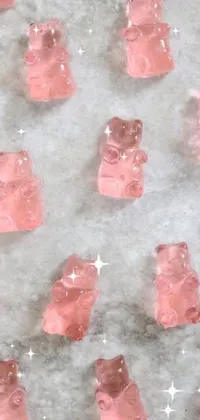 This phone live wallpaper features a vibrant table filled with a plethora of pink gummy bears and refreshing ice cubes