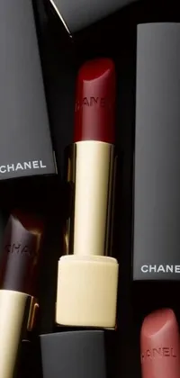 This phone live wallpaper features a chic arrangement of Chanel lipsticks against a dark red and black color palette