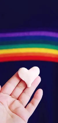 This phone live wallpaper features a heart-shaped marshmallow in a person's open hand, surrounded by an ethereal rainbow nimbus crafting a whimsical and uplifting atmosphere
