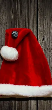 This live phone wallpaper features a cheerful red Santa hat sitting atop a rustic wooden wall