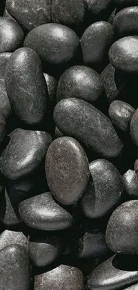 Looking for a unique and captivating live wallpaper for your phone? Look no further than this stunning image of a pile of black rocks sitting on a table