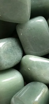This live wallpaper for your phone features a pile of smooth and polished green rocks on a wooden table