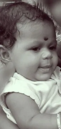 This captivating live wallpaper depicts a heartwarming close-up of a person holding a baby in a black and white photo