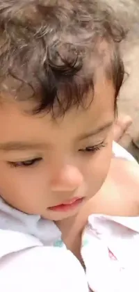 This mobile live wallpaper features a close-up shot of a young child holding a smartphone
