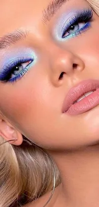 This phone live wallpaper features a close-up of a stunning woman with gorgeous blue eyes and a unique pastel makeup look