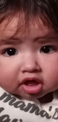 This phone live wallpaper features a close-up of a person holding a baby, with a surprised expression on their face