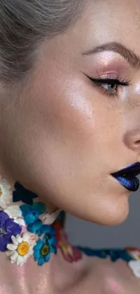 This phone live wallpaper features a close up of a floral decorated woman, showcasing glossy iridescence and dark blue lipstick
