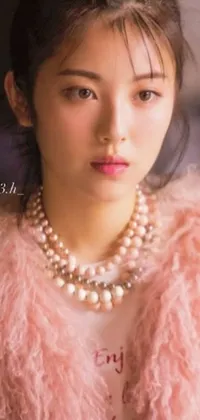 This live wallpaper features a fashionable woman in a pink fur coat and pearl necklace standing in front of a picturesque backdrop