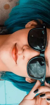 This blue-haired woman phone live wallpaper features a young girl wearing square sunglasses, looking up with wonder against a vibrant phthalo blue background