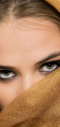 This captivating live wallpaper exhibits a woman with a scarf wrapped around her head, showcasing her striking brown almond-shaped eyes