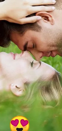 This phone live wallpaper features a passionate couple sharing a close-up kiss in a lush green field
