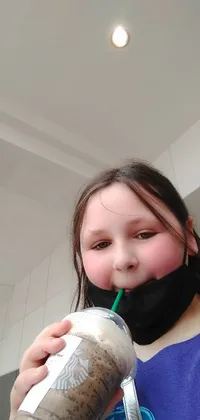 This live phone wallpaper features an image of a young girl savouring a drink from a Starbucks cup