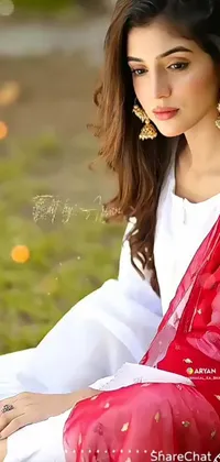 The phone live wallpaper depicts a beautiful woman sitting on a lush green landscape with fields of red and white flowers in the background