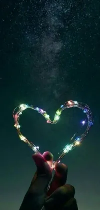 This stunning phone live wallpaper features a heart-shaped string of colorful lights against a backdrop of a beautiful space-themed image, making it a perfect choice for those who love bright colors and dreamy atmosphere on their phones