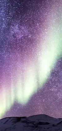 Enjoy the beauty of nature and space with this stunning phone live wallpaper featuring a group of individuals standing atop a snow-covered hill