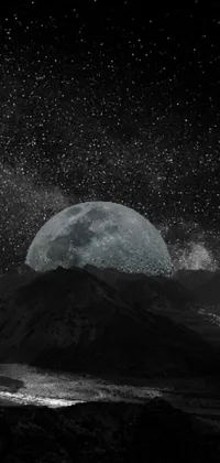 This stunning phone live wallpaper features a digital art black and white photograph of a full moon rising from a majestic mountain range against a backdrop of a starry night sky