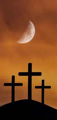 This phone live wallpaper showcases a hauntingly captivating image of three crosses on a hill, with a stunning moon in the background