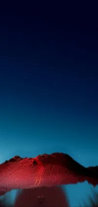 This phone live wallpaper showcases a beautiful red mountain situated in a barren desert with a deep blue night sky adding to its appeal