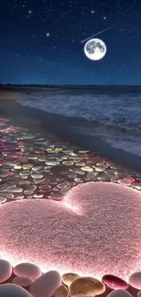 This phone live wallpaper features a digital rendering of a pink heart on a beach next to the ocean at night, with the moonlight illuminating the heart and beach, and the stars twinkling in the sky above